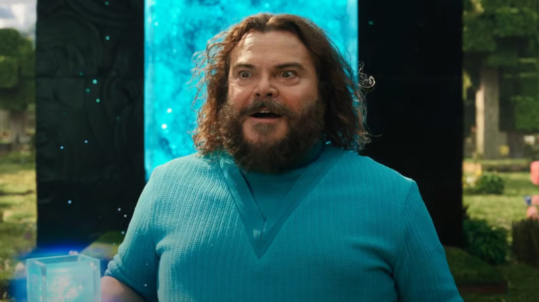 Steve holding a blue cube in front of a blue portal in A Minecraft Movie