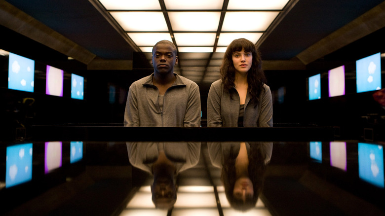 Bing and Abi surrounded by TV screens in a room in Black Mirror