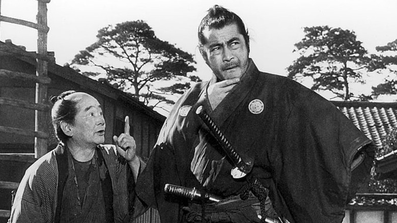 Toshiro Mifune as Kikuchiyo converses with Bokuzen Hidari as Yohei in Seven Samurai