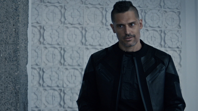 Joe Manganiello as Tomm Schultz standing in front of a white geometric wall on Moonhaven