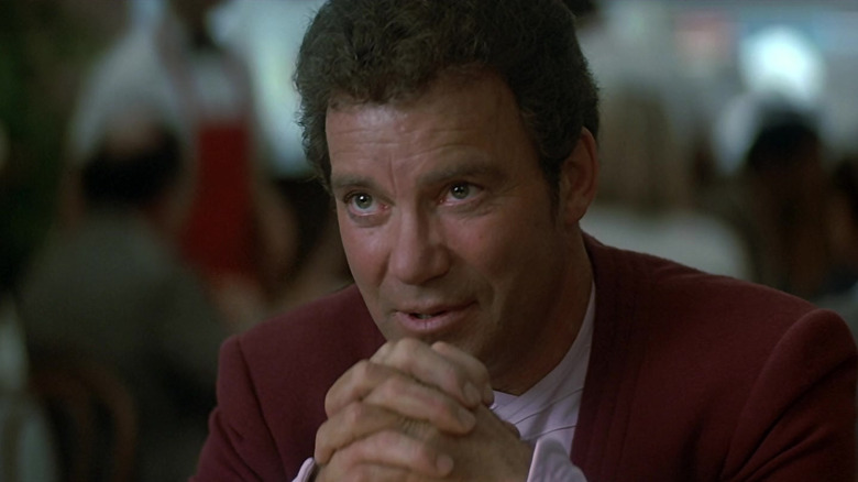 William Shatner interlacing his fingers while listening as Kirk in Star Trek IV: The Voyage Home
