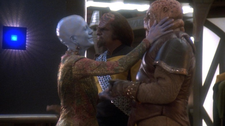 Worf walking past Morn and a blue woman on Star Trek: Deep Space Nine.