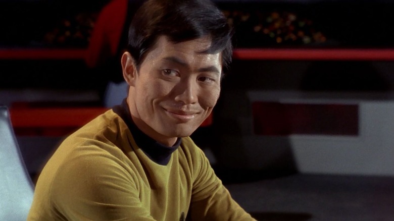 Sulu bij de conn, glimlachend, op Star Trek