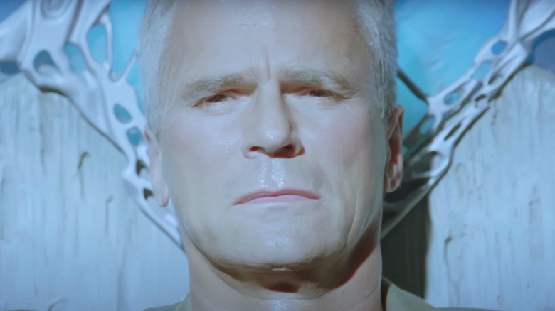 Richard Dean Anderson's Jack O'Neill looks into camera while illuminated by a bright light in Stargate SG-1