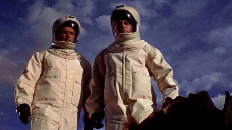 హజ్మత్ సూట్‌లో ఉన్న ఇద్దరు వైద్యులు ఆండ్రోమెడ స్ట్రెయిన్‌లో మృతదేహాన్ని చూస్తున్నారు