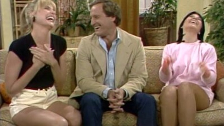 Terri, Leslia, and Janet laughing on a couch in Three's Company