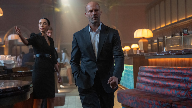 Jason Statham as Levon Cade walking through a bar dressed in a tailored suit in A Working Man