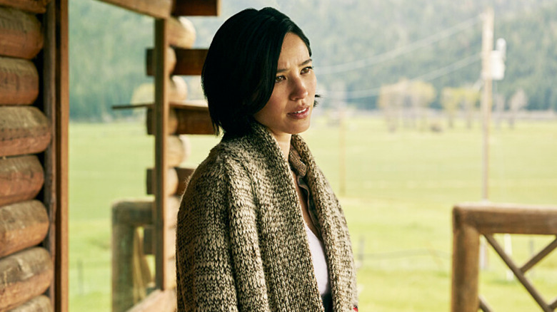 Kelsey Asbille's Monica Dutton stands on the porch of a house in Yellowstone