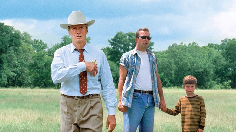 Clint Eastwood as Chief Red Garnett, Kevin Costner as Butch Haynes and T.J. Lowther as Phillip Buzz Perry stand in a field in A Perfect World
