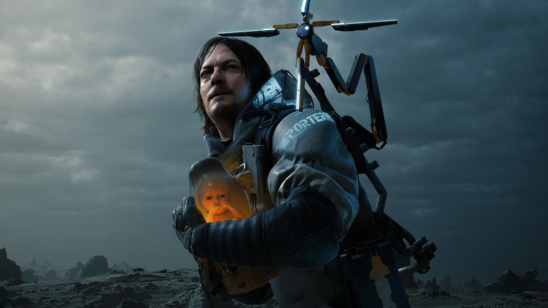 Sam Porter carries a baby through a wasteland in Death Stranding