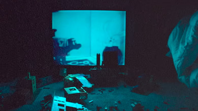 Games on the ground in front of a glowing TV in Skinamarink