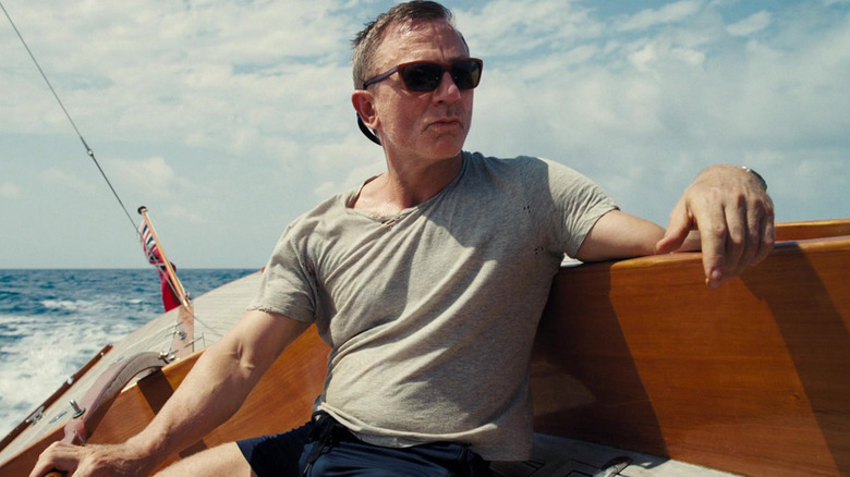 Daniel Craig as James Bond steers a boat in No Time to Die
