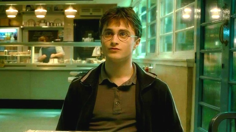 Daniel Radcliffe as Harry Potter sitting at a table