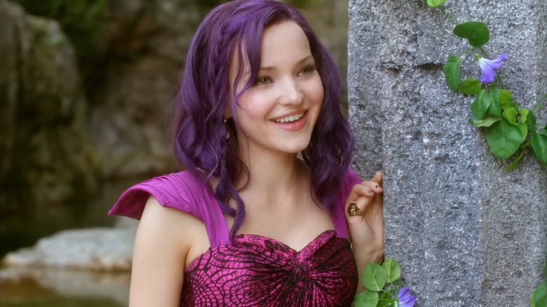 Mal (Dove Cameron) sings while standing against a stone column, in Descendants
