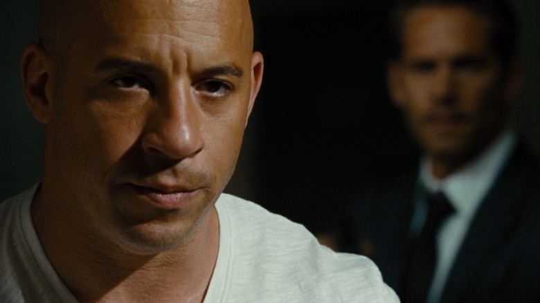 Dominic Toretto (Vin Diesel) in a white shirt, with Brian (Paul Walker) out of focus behind him, from Fast & Furious