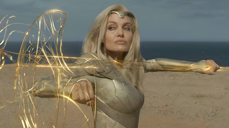 Angelina Jolie as Thena standing with an energetic spear and shield in Eternals