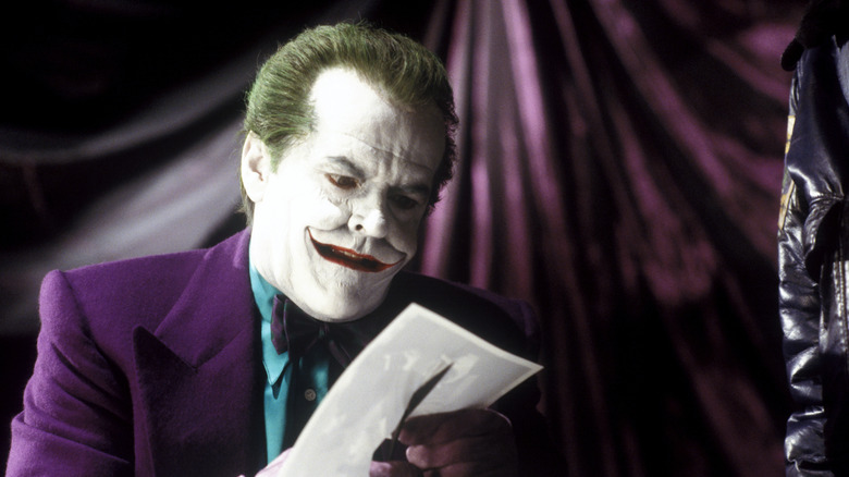 Jack Nicholson as The Joker looking at a piece of paper in Batman