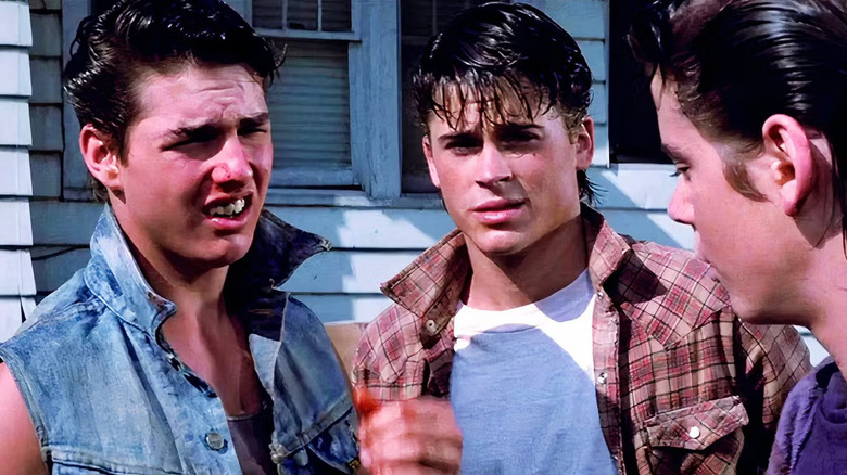 Tom Cruise as Steve Randle and Rob Lowe as Sodapop "Soda" Curtis looking annoyed talking to a friend in The Outsiders.