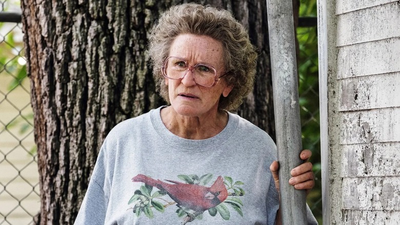 Mamaw scowling outside of her house in a cardinal sweatshirt in Hillbilly Elegy