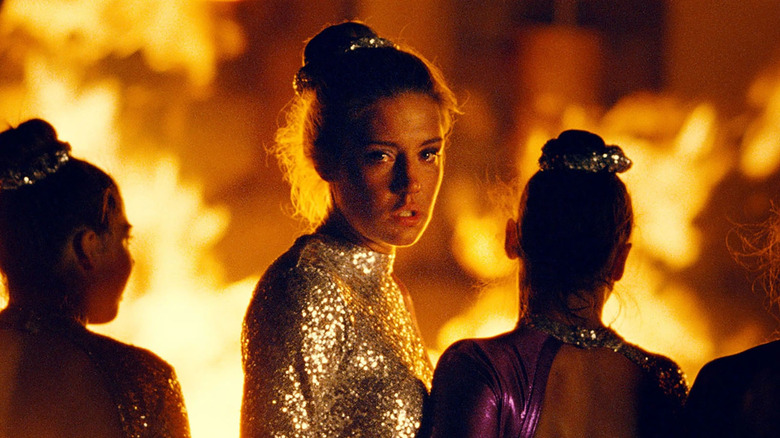 Adèle Exarchopoulos looking back toward the camera in a sparkly leotard with fire behind her in the film the five devils
