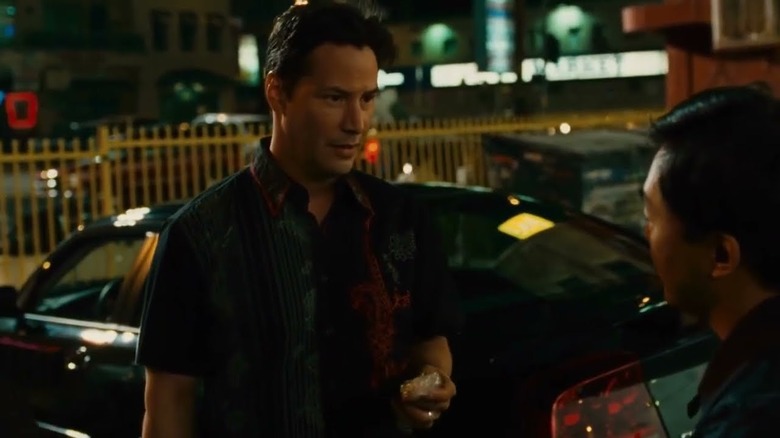 Keanu Reeves as Detective Tom Ludlow standing next to a car in Street Kings