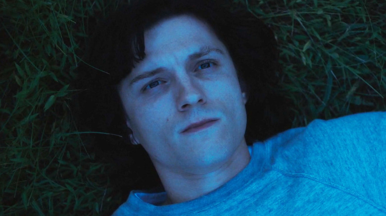 Tom Holland's Danny Sullivan is seen laying on grass looking up in The Crowded Room