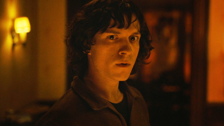 Tom Holland's Danny Sullivan stands in a dimly lit corridor looking worried in The Crowded Room