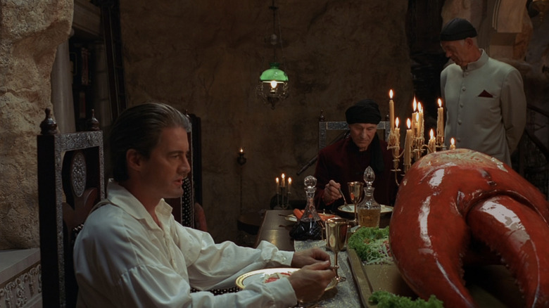 Kyle MacLachlan's Cyrus Smith sits at a luxurious dinner table with Patrick Stewart's Captain Nemo in Mysterious Island