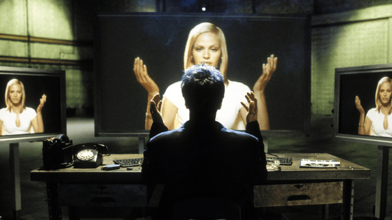 Victor Taransky (Al Pacino) sits with his hands with three screens from Simon (Rachel Roberts) in S1M0NE