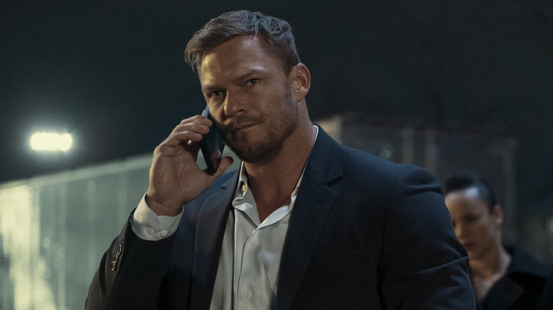 Reacher in a suit listening on a phone
