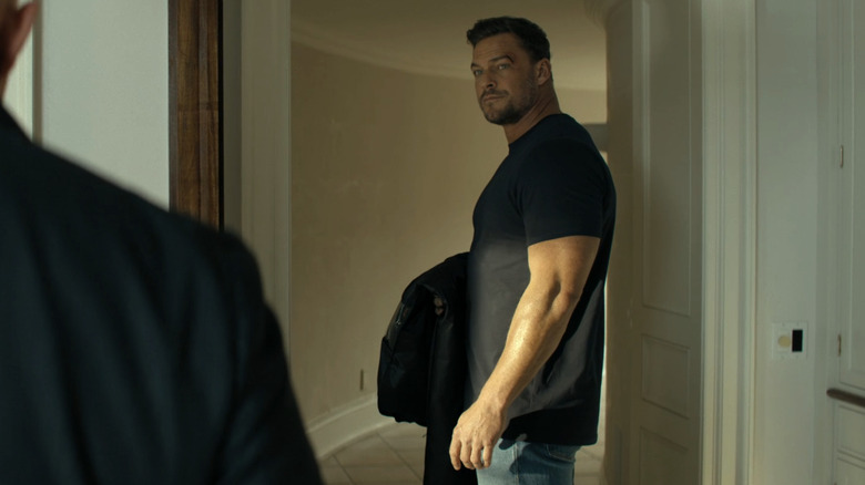 Alan Ritchson as Jack Reacher is seen standing in a doorway in Reacher