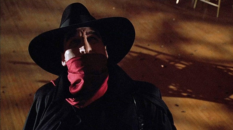 Alec Baldwin as Lamont Cranston wearing a mask and hat in The Shadow