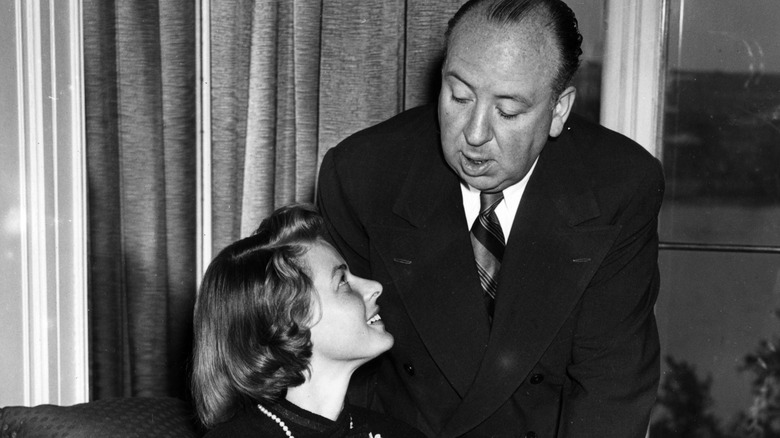 Hitchcock talking to actress Ingrid Bergman in a chair