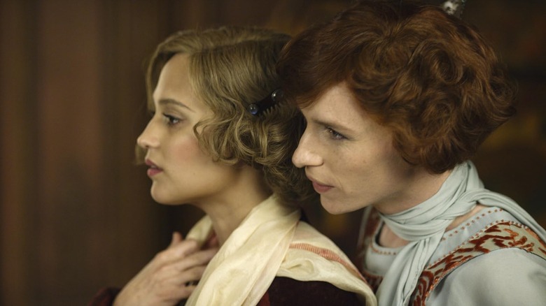 Eddie Redmayne as Lili Elbe stands behind Alicia Vikander as Gerda Wegener in The Danish Girl