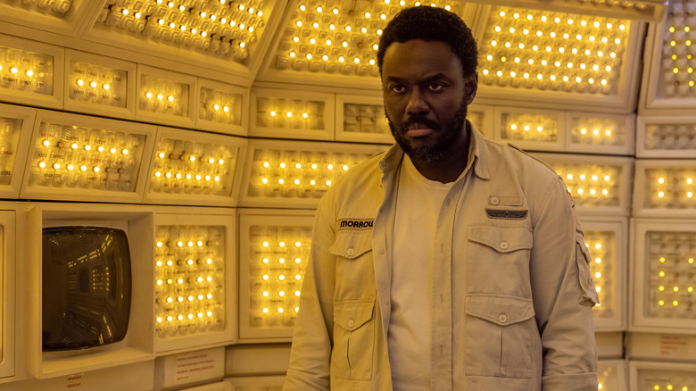Babou Ceesay as the cyborg Morrow standing in a brightly-lit, dome-shaped room with a computer in Alien: Earth