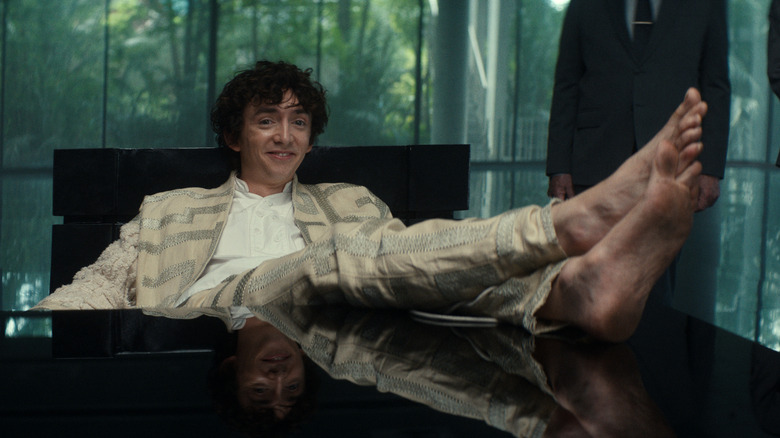 Boy Kavalier smirking like an idiot with his bare feet up on his desk in Alien: Earth