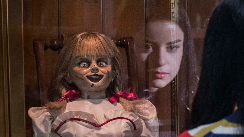 Daniela's face is reflected in the case containing Annabelle in Annabelle Comes Home