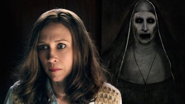 Lorraine Warren looks around in the darkness while a creepy painting of the Nun lurks behind her in The Conjuring 2