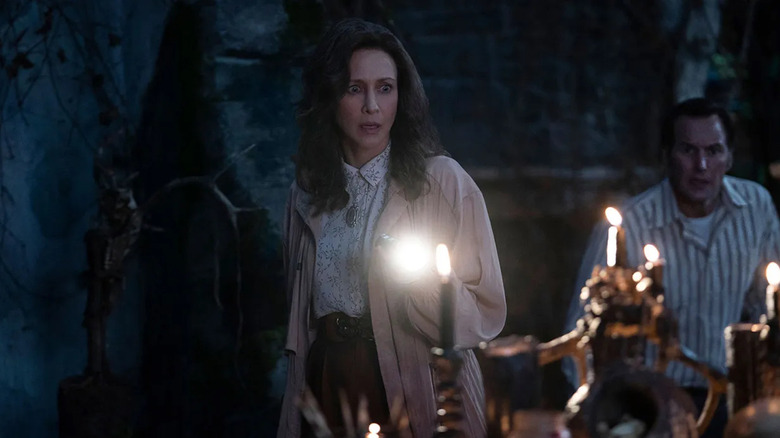 Lorraine and Ed Warren, both looking shocked, explore an underground lair in The Conjuring: The Devil Made Me Do It