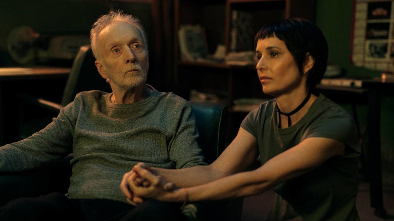 Tobin Bell as John Kramer/Jigsaw and Shawnee Smith as Amanda Young holding hands as Kramer looks at something in Saw X