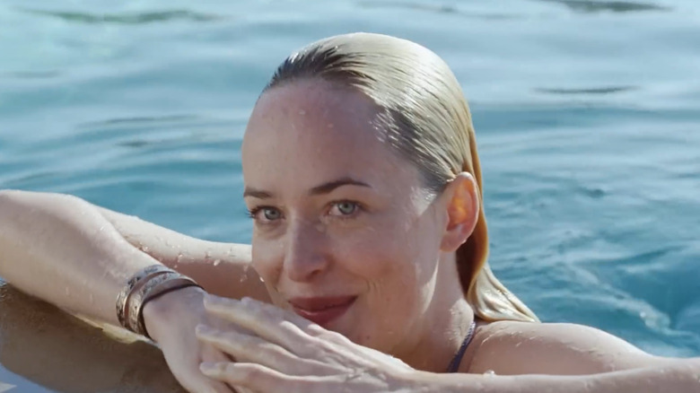 Dakota Johnson as Penelope Lanier, wading at the edge of a pool in A Bigger Splash