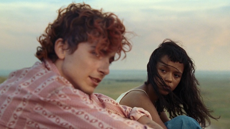 Taylor Russell and Timothée Chalamet as Maren and Lee, sitting together outdoors in Bones and All