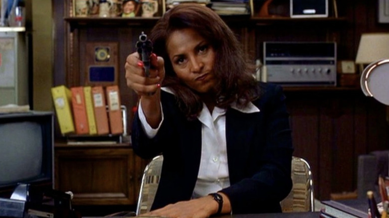 Pam Grier as Jackie Brown sitting down and pointing a gun in Max Cherry's office in Jackie Brown