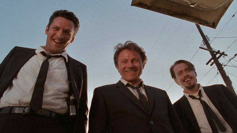 Michael Madsen as Vic Vega AKA Mr. Blonde, Harvey Keitel as Larry Dimmick AKA Mr. White, and Steve Buscemi as Mr. Pink standing outside and laughing at the cop in a Blonde's trunk in Reservoir Dogs