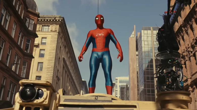 Tom Holland in costume as Spider-Man, standing on top of a tank on the set of Spider-Man: Brand New Day