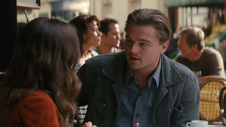 Leonardo DiCaprio as Dom Cobb talking to Elliot Page as Ariadne in Inception at an outdoor cafe.