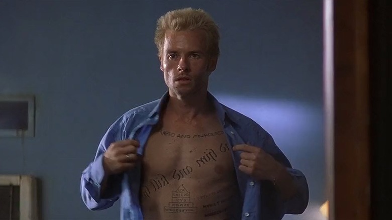 Guy Pearce as Leonard Shelby in Memento, observing his tattooed body in a mirror.