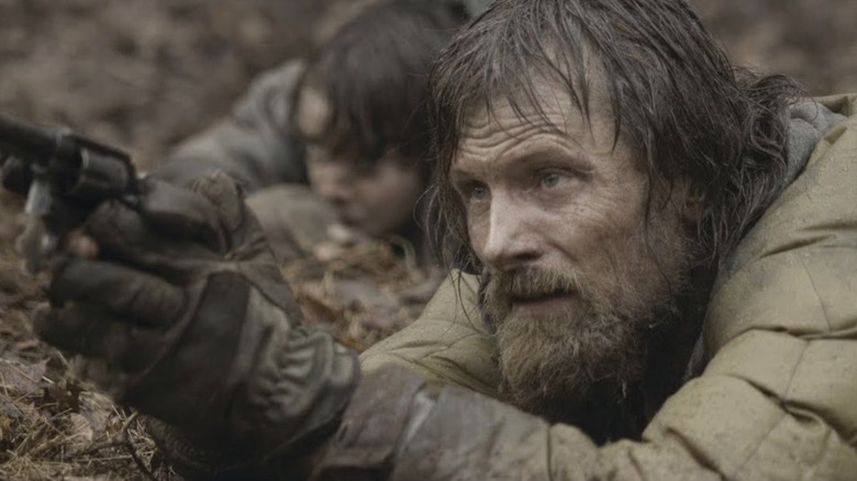 The man (Viggo Mortensen) and the boy (Kodi Smit-McPhee) hide in a ditch with a gun in The Road