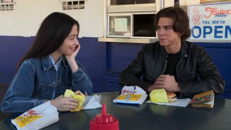 Mikey Madison as Liza and Sean H. Scully as Brett smiling and looking at each other in Liza, Liza, Skies Are Grey
