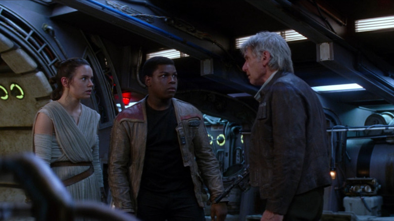 Rey (Daisy Ridley) and Finn (John Boyega) staring at Han Solo (Harrison Ford) in The Force Awakens